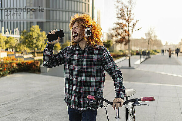 Glücklicher Mann hält Smartphone in der Hand und hört unterwegs Musik