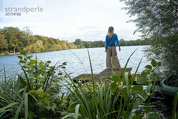 Frau steht am Steg vor dem See