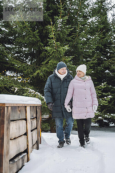 Lächelndes älteres Paar  das im Winter auf dem Fußweg spaziert