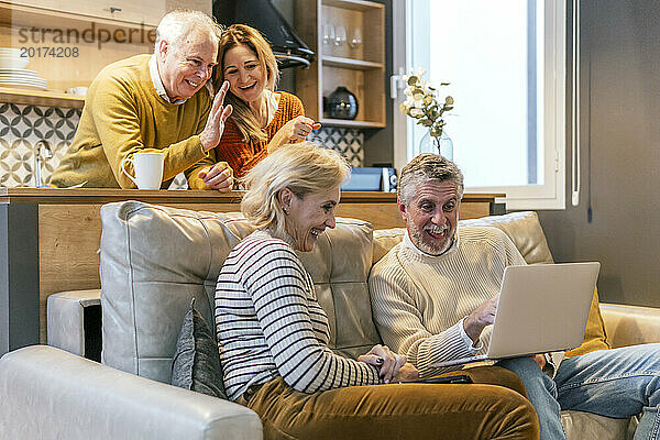 Fröhliche Freunde unterhalten sich per Videoanruf im Wohnzimmer zu Hause