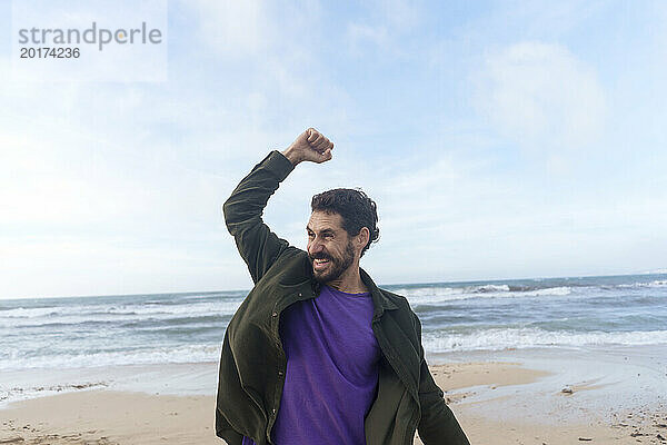 Happy man cheering in front of sea at beach