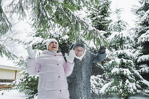 Sorgloses älteres Paar  das im Winter mit Schnee spielt