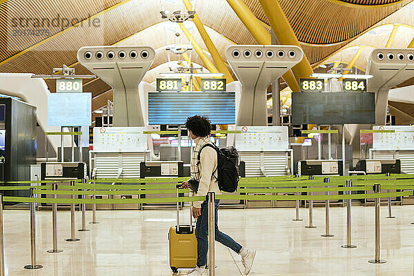 Junger Mann mit Gepäck geht am Flughafen spazieren
