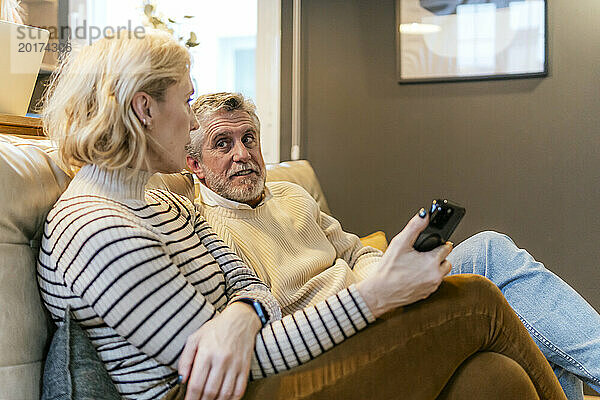Mann spricht mit Frau  die zu Hause auf dem Sofa sitzt