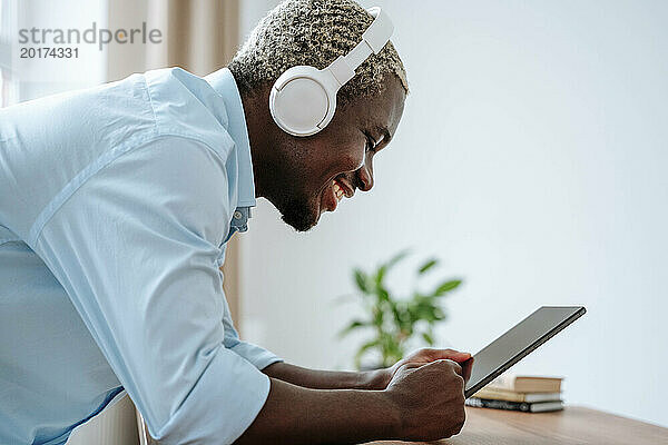 Glücklicher Mann mit kabellosen Kopfhörern und Tablet-PC