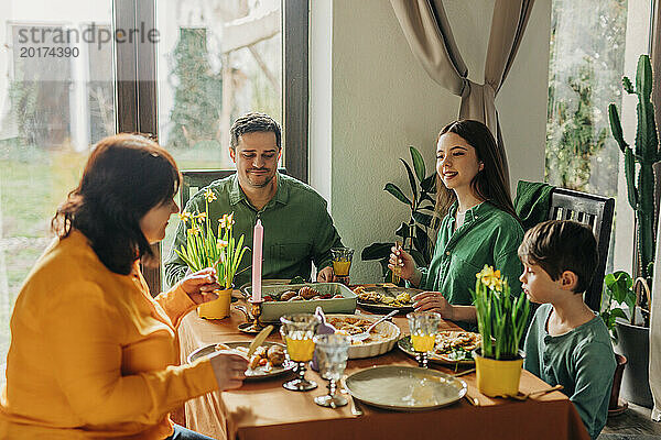 Glückliche Familie genießt das Essen am Esstisch beim Osteressen