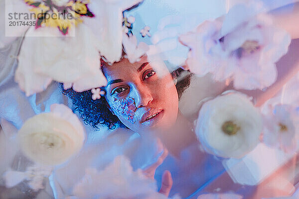 Schöne Frau liegt hinter einer Glasoberfläche mit Blumen
