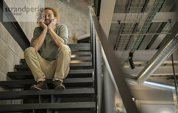Verärgerter Geschäftsmann sitzt auf der Treppe im Büro