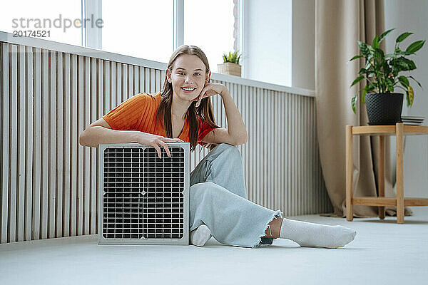Lächelnde schöne Frau sitzt mit Solarpanel zu Hause