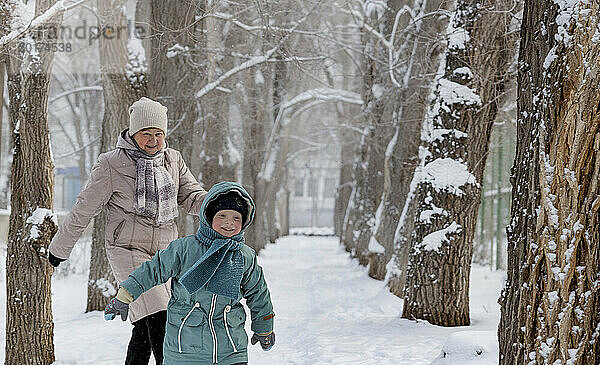 Glückliche ältere Frau  die im Winter mit ihrem Enkel im Park spielt