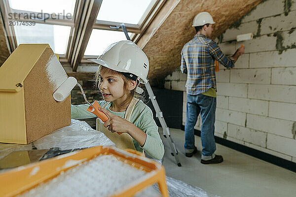 Mädchen trägt Schutzhelm und hilft Vater bei Renovierungsarbeiten