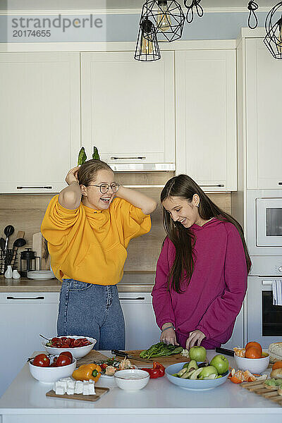 Cheerful friends preparing food in kitchen at home