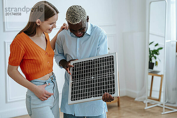Glücklicher Mann und Frau diskutieren zu Hause über Solarpanel