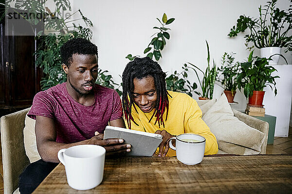 Mann teilt Tablet-PC mit Freund zu Hause