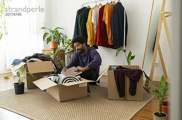 Mann organisiert Kleidung und Gegenstände in Pappkartons