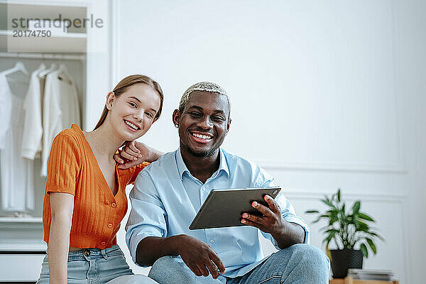 Glückliches junges Paar sitzt zu Hause mit Tablet-PC