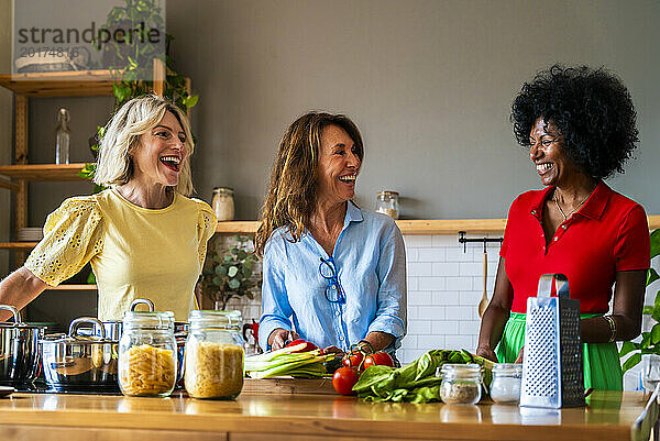 Glückliche Frauen  die zu Hause Essen zubereiten und in der Küche lachen
