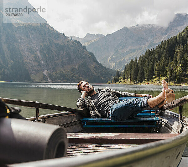 Young man relaxing in boat at lake Vilsalpsee near mountains  Tyrol  Austria