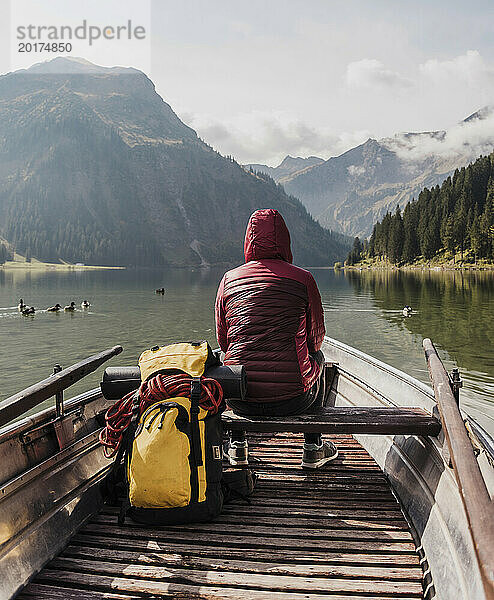 Junge Frau mit Rucksack sitzt im Boot am Vilsalpsee in der Nähe von Bergen  Tirol  Österreich