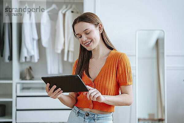 Lächelnde junge Frau  die zu Hause einen Tablet-PC benutzt