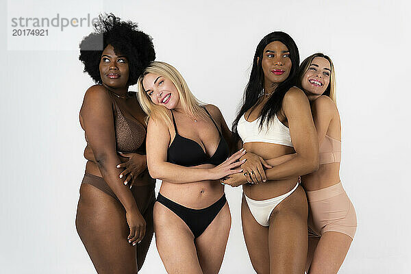 Attractive women and non binary person wearing lingerie against white background
