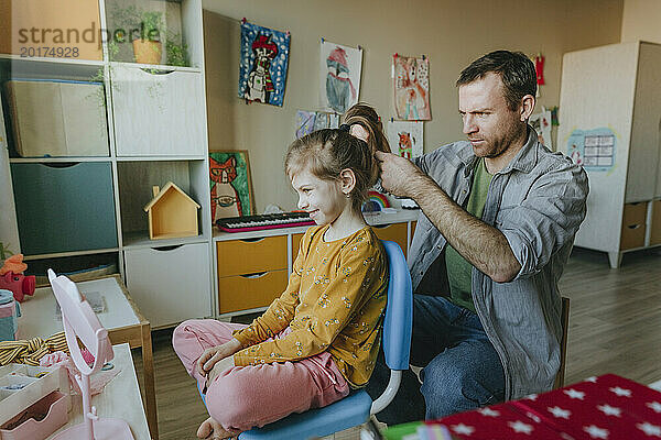 Vater bindet seiner Tochter zu Hause die Haare