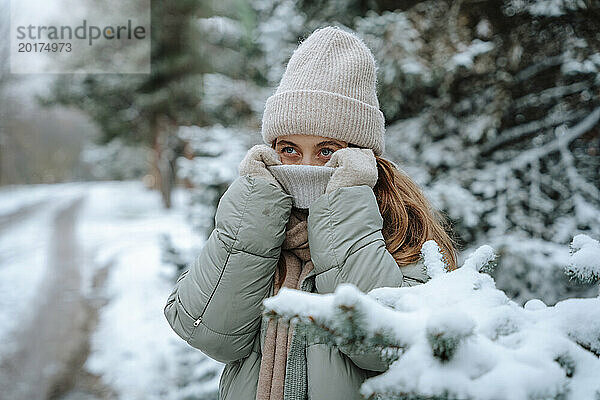 Verspielte Frau bedeckt Gesicht im Winter mit Pullover