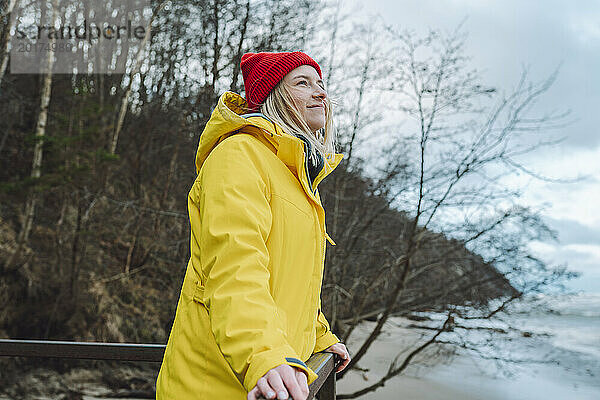 Lächelnde Frau in Winterjacke am Strand