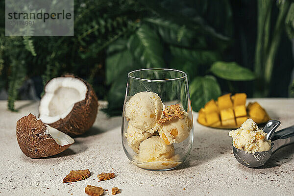 Mango-Kokos-Eis im Glas neben dem Servierlöffel