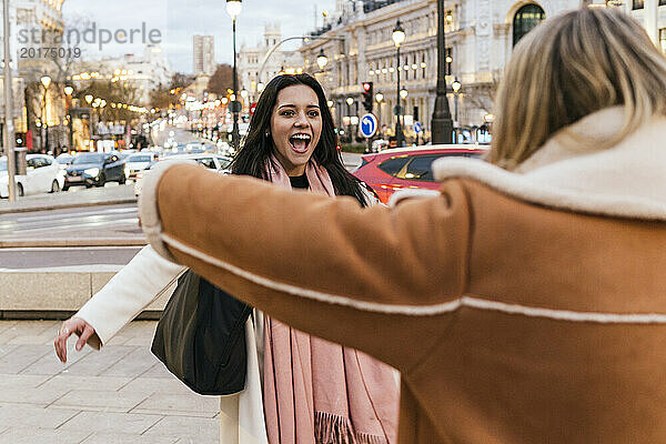 Aufgeregte Frau begrüßt Freundin  die auf der Straße in der Stadt steht
