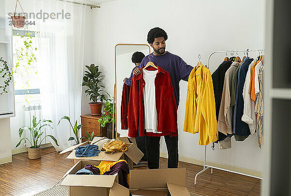 Mann organisiert und entrümpelt Kleidung zu Hause