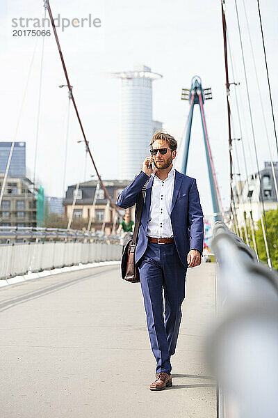 Geschäftsmann läuft mit Smartphone auf Brücke in der Stadt