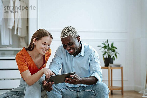 Glücklicher junger Mann und Frau  die zu Hause einen Tablet-PC nutzen