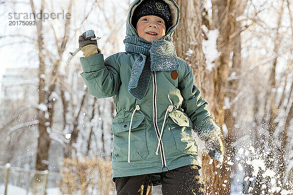 Smiling boy throwing stick in snow