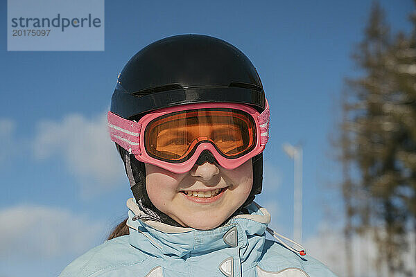 Lächelndes Mädchen mit Skibrille im Resort