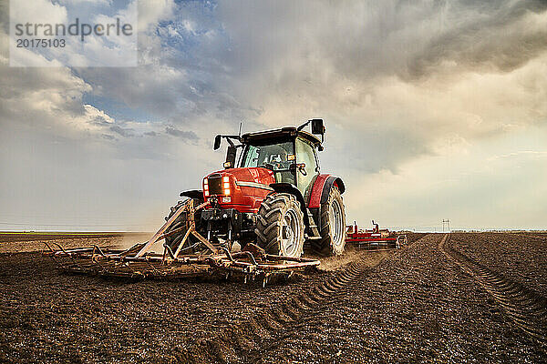 Landwirt pflügt Feld mit Traktor an bewölktem Tag