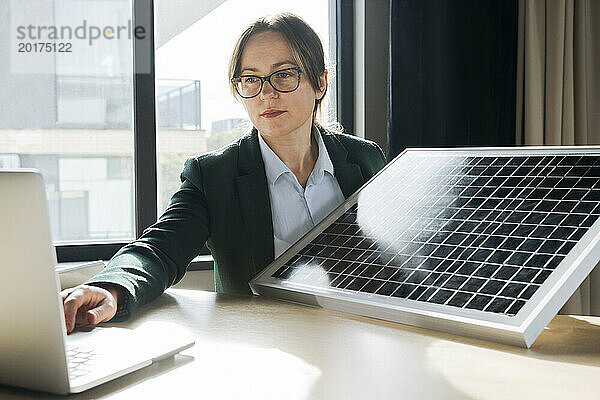 Ingenieur zeigt Solarpanel bei Videoanruf über Laptop im Büro