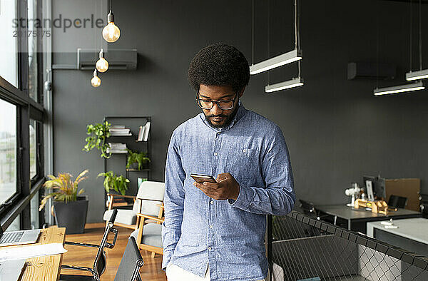 Junger Geschäftsmann nutzt Smartphone im Büro