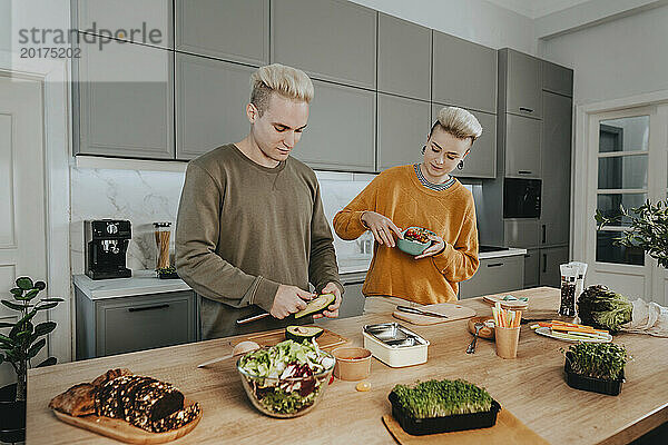 Junges Paar bereitet gesundes Essen für Lunchboxen zu