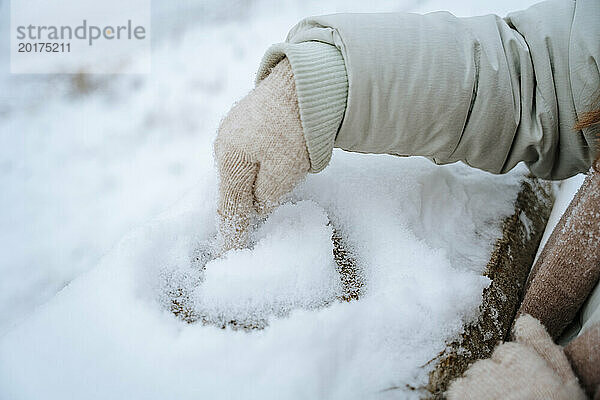 Frau macht im Winter Herzform auf Schnee