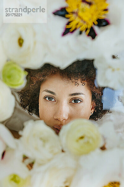 Junge Frau hinter Glasoberfläche mit Blumen