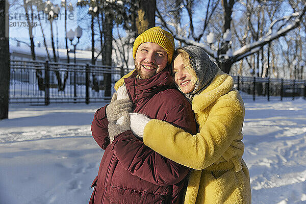 Lächelnde Frau umarmt Mann im Winter