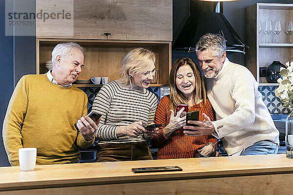 Glückliche Freunde  die zu Hause gemeinsam ihr Smartphone nutzen