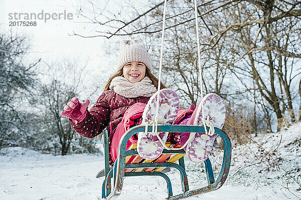 Fröhliches Mädchen  das im Winter eine Schlittenfahrt auf dem Schnee genießt