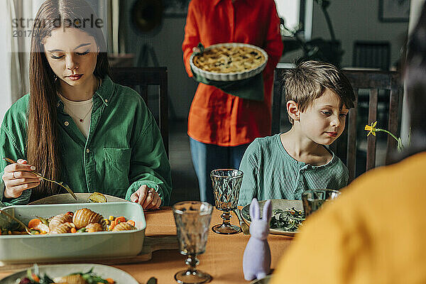 Siblings eating meal on dining table at Easter dinner celebration
