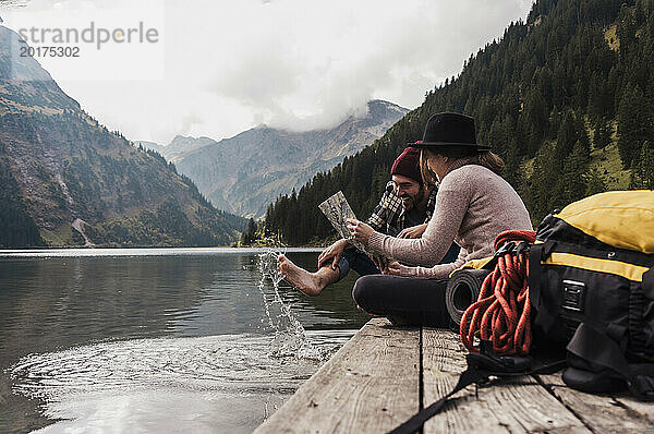 Glückliches Paar sitzt mit Karte am Pier in der Nähe des Vilsalpsees und der Berge in Tirol  Österreich