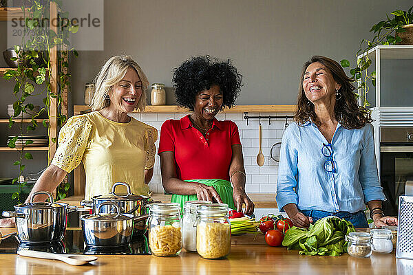 Glückliche Frauen bereiten gemeinsam in der Küche zu Hause Essen zu