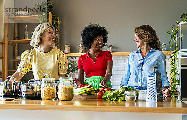 Lächelnde Frauen bereiten gemeinsam in der Küche zu Hause Essen zu