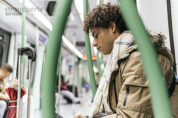 Junger Mann mit lockigem Haar reist im Zug