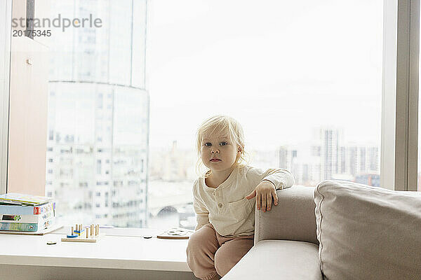 Kleines Mädchen sitzt zu Hause auf der Fensterbank